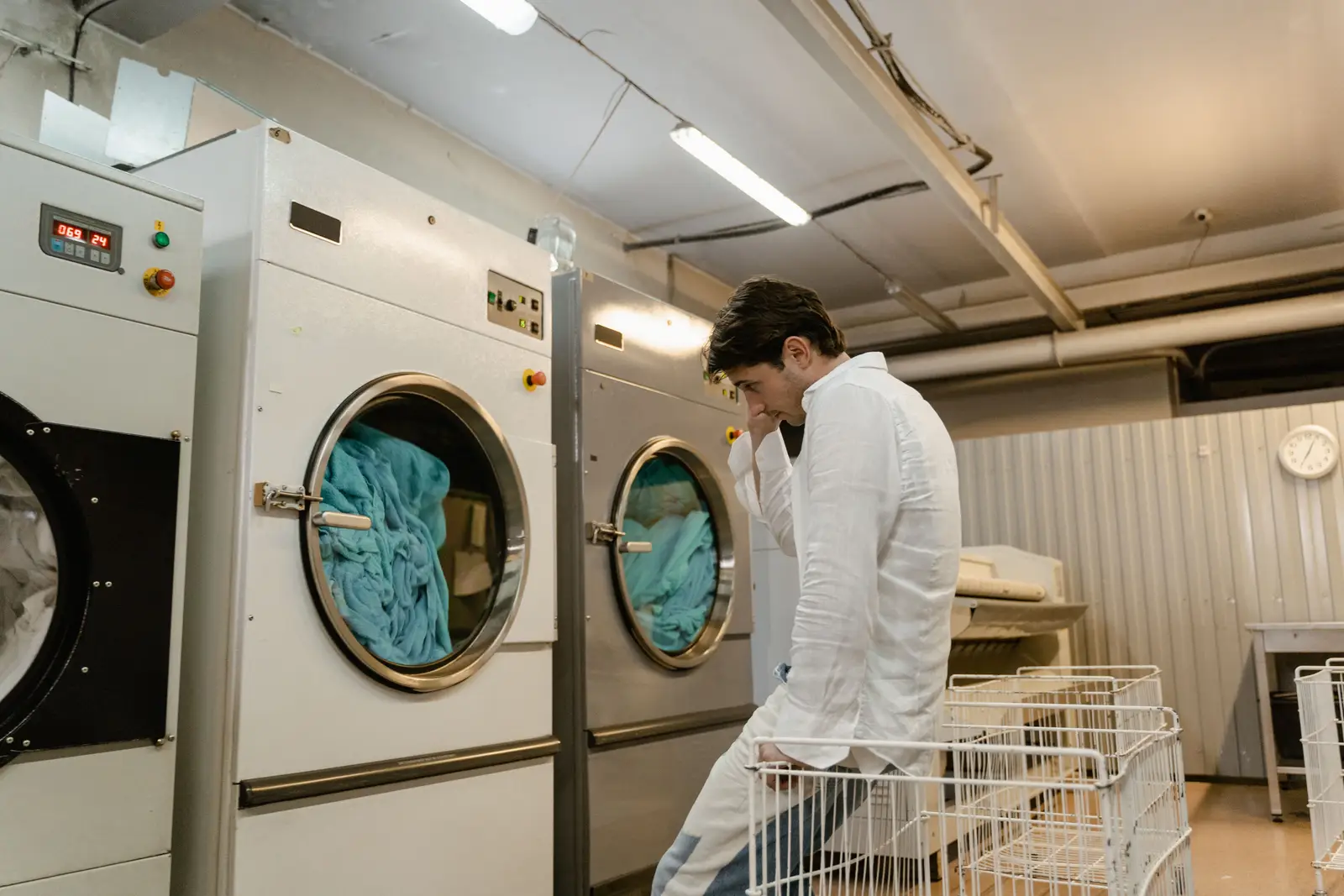 A laundry professional working beside industrial washing machines